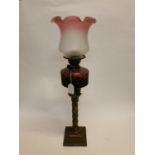 Brass corinthian column oil lamp with red glass bowl and etched tulip shade. (80 cm H).