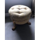 Regency style centre stool with deep buttoned upholstery standing on hairy paw feet