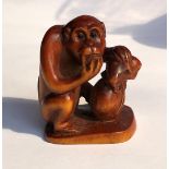 JAPANESE NETSUKE OF A CROUCHING MONKEY WITH A BAG