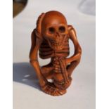 JAPANESE NETSUKE OF A SEATED SKELETON HOLDING A RIBBON TIED BAG