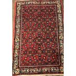 2OTH CENTURY CARPET WITH LOZENGE AND MOTIFS ON A RED GROUND WITHIN A BORDER,