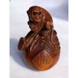 JAPANESE WOOD CARVED NETSUKE OF A CROUCHING MONKEY ON A GOURD.