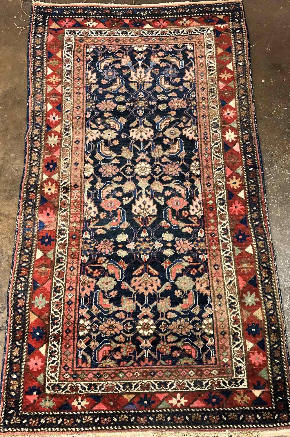 20 TH CENTURY CAUCASIAN CARPET WITH CENTRAL FLORAL MOTIFS ON A BLUE GROUND WITHIN GEOMETRIC PATTERN