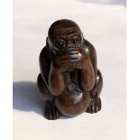 JAPANESE CARVED HARDWOOD NETSUKE OF A CROUCHING MONKEY