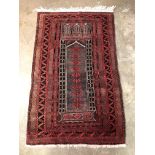 20TH CENTURY CAUCASIAN PRAYER RUG WITH LOZENGE AND GEOMETRIC MOTIFS ON A RED GROUND WITHIN A