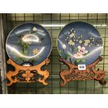 PAIR OF 20TH CENTURY CLOISSONNE ENAMEL 21CM BOTANICAL SHALLOW DISHES ON CARVED HARDWOOD STANDS