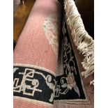 CHINESE PINK AND BLACK WOOLEN CARPET AND A BLACK AND CREAM WOOLEN CARPET