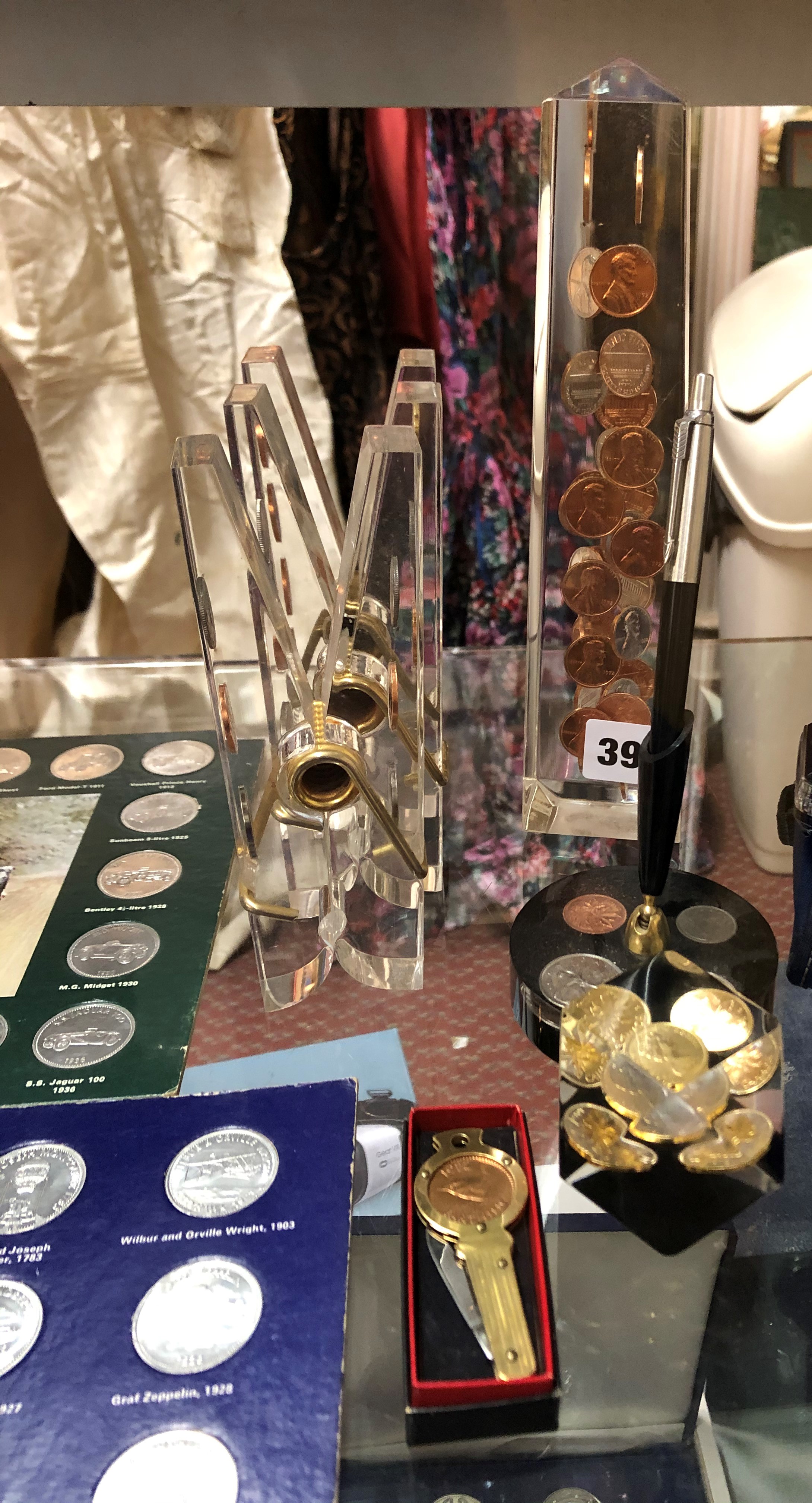 SELECTION OF NOVELTY COIN INSET PERSPEX PEG AND MONUMENT PAPERWEIGHTS AND A DESK STAND