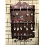 PINE STAINED RACK OF SOUVENIR AND ENAMEL FINIAL TEASPOONS