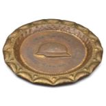 A German ‘Stahlhelm’ art deco style brass plate, 15½” diam, the rim with embossed decoration, the