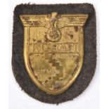 A Third Reich brass Kuban shield, on field grey cloth patch with paper backing. GC