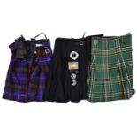 2 tartan kilts; another plain black and another plain dark green; 2 base metal clan brooches and a