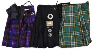 2 tartan kilts; another plain black and another plain dark green; 2 base metal clan brooches and a