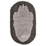 A Third Reich Demjansk shield, of grey zinc on field grey patch with original paper backing.
