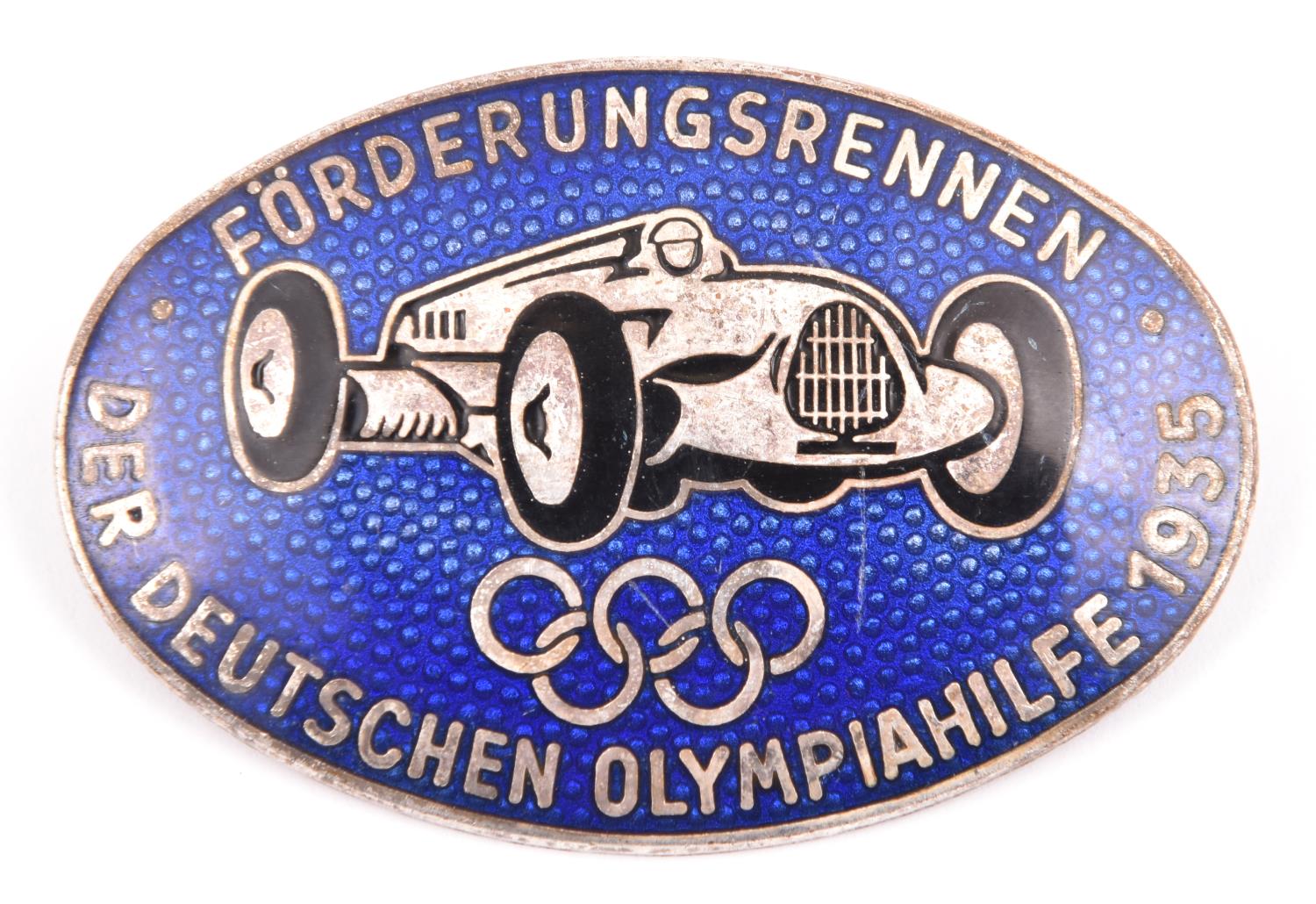 A Third Reich oval silver and enamelled pin back badge, depicting an Auto Union racing car above the