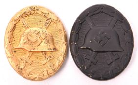 A Third Reich wound badge, in gold with solid back marked “L/14”; and another, hollow back in