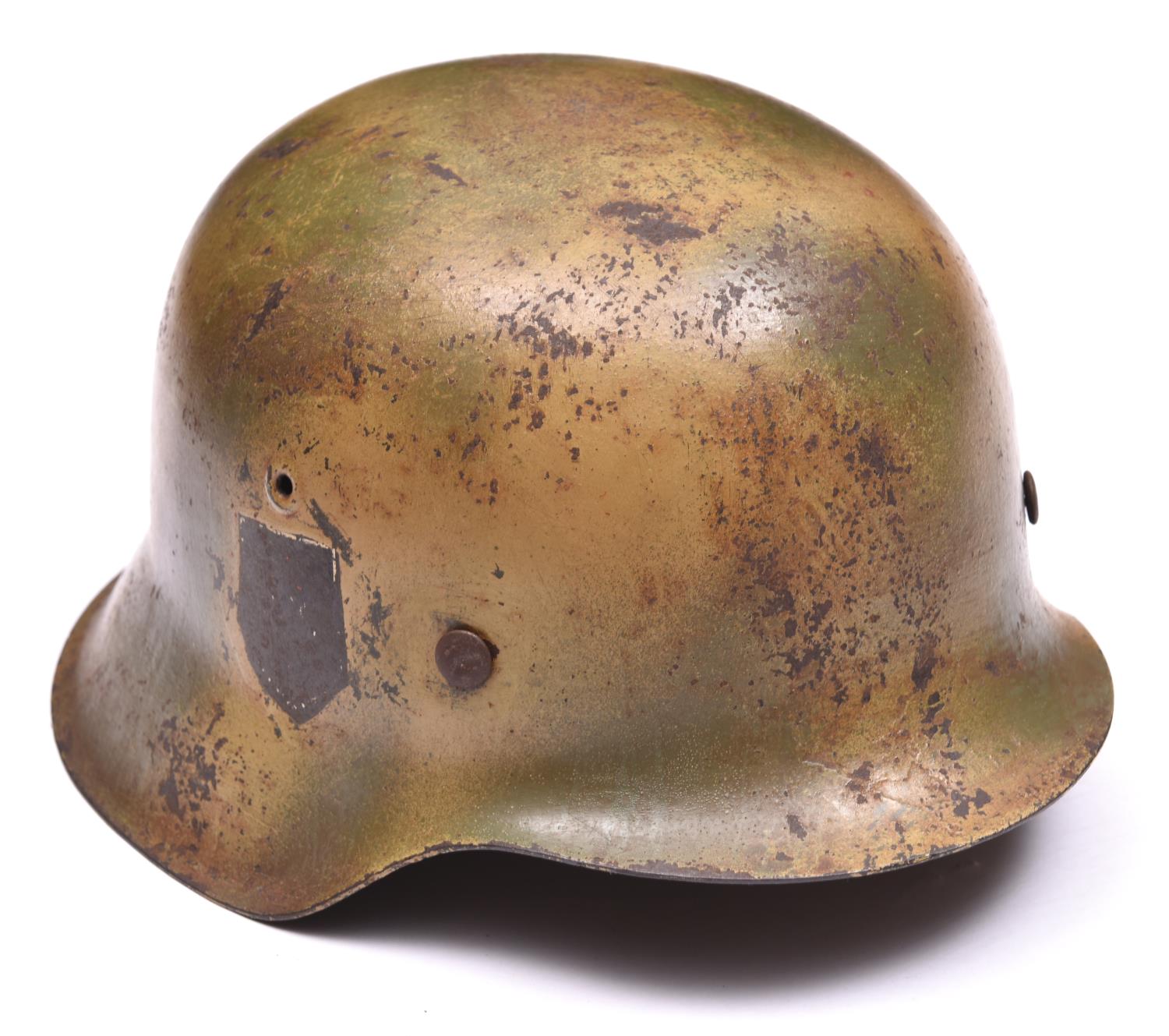 A Third Reich M42 steel helmet, with camouflage finish, the single decal removed, maker’s mark “