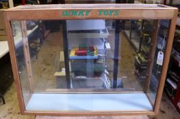 A Dinky Toys oak display cabinet with glass to 5 sides. 'Dinky Toys' in green lettering to top.
