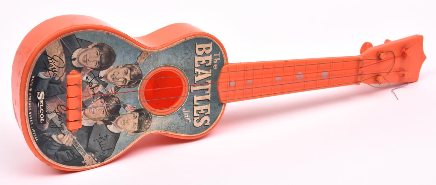 A Beatles Selcol Junior Guitar. A 1963 issued orange plastic guitar with 4 nylon strings in