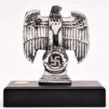 A Third Reich small cast polished aluminium desk eagle, mounted on a heavy solid brass rectangular