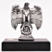 A Third Reich small cast polished aluminium desk eagle, mounted on a heavy solid brass rectangular