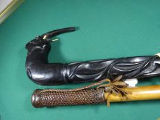 A malacca walking stick, 33½” with wood and leather handle; a heavily carved ebony walking stick