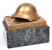 A Swiss Army brass paperweight, with marble base, depicting a helmet and bayonet. GC £50-60.