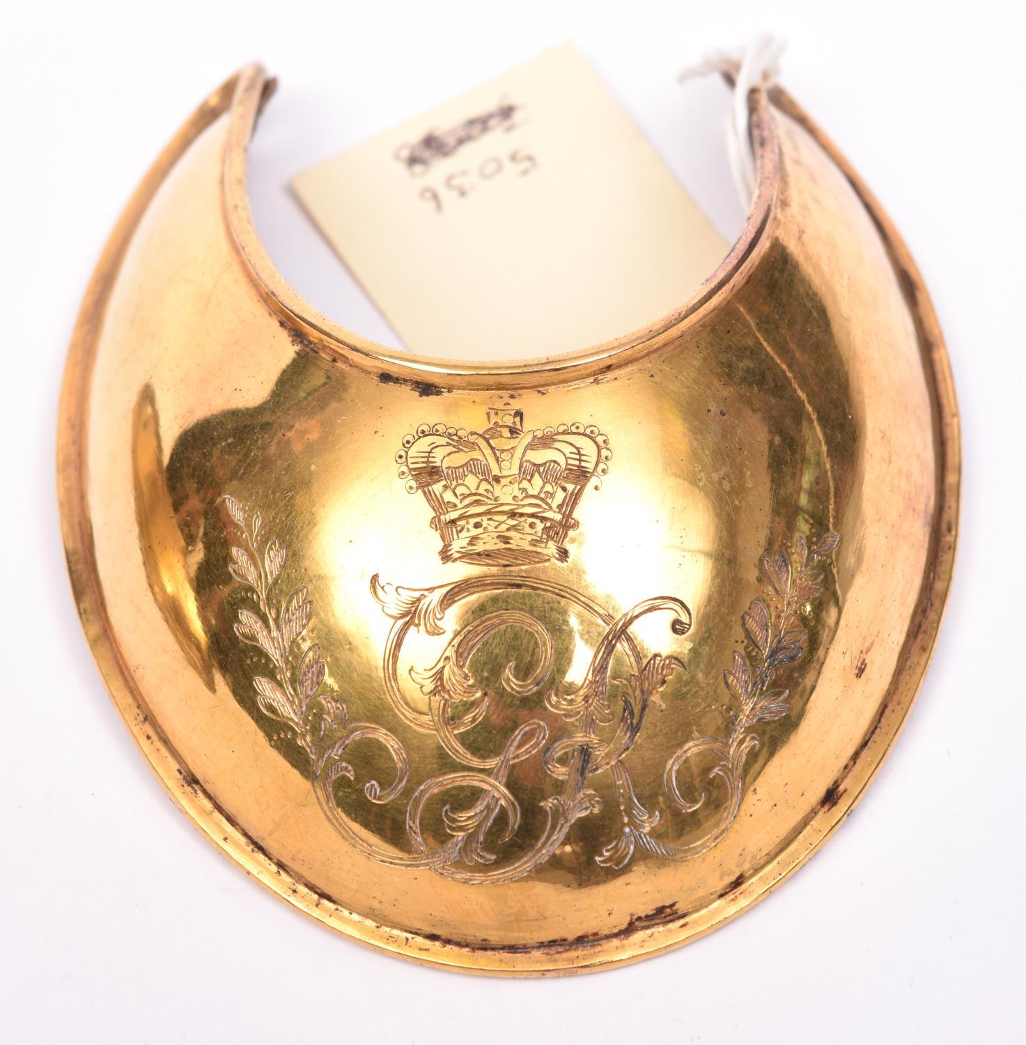 A George III officer’s gilt gorget, engraved with the Royal cypher, with chamois liner. Very Good