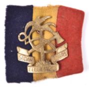 A scarce brass cap badge of the Sudan Elec & Mech Engrs, with original red, black and yellow cloth