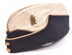 A post 1922 Officer’s field cap of the 13th/18th Hussars, white top, GM cap badge and plain