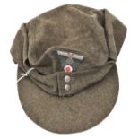 A Third Reich field grey soft peaked cap, with one piece Bevo woven eagle and cockade, beaded