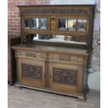 An Edwardian Arts & Crafts style oak sideboard with mirrored back having flared and dentilated