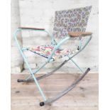 A vintage folding metal rocking chair with plywood armrests.