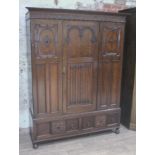 A 1920s three piece oak bedroom suite comprising wardrobe, chest of drawers and dressing table,
