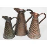 A group of three Arts and Crafts graduated crocodile effect "Neptune" copper jugs by Joseph Sankey.