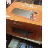 A boxed orange Swan Retro 20 L capacity microwave.