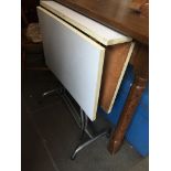 A white drop leaf table with chrome base