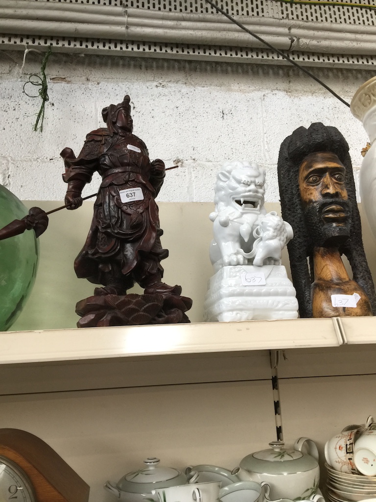 A Chinese hardwood figure, White pottery dog of foe and an ethnic carved head figure