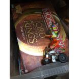 A box of boxed games including Lord of the Rings and a tin plate toy.