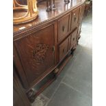 An oak sideboard with rail back and carved panels