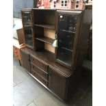 An Ercol dark elm sideboard, the top section with central open cabinet and shelf flanker either side