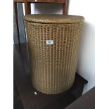 A gold coloured Lloyd Loom linen basket