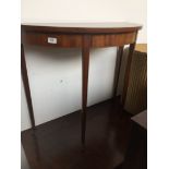 A mahogany half moon side table on tapered legs with ceramic castors