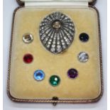 An Art Deco white metal brooch with interchangeable studs including one ruby and six coloured