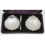 A cased pair of silver half clam butter dishes with glass liners and one knife, Levesley Brothers,