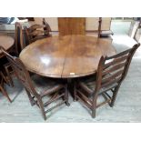 A reproduction oak extending pedestal dining table with single leaf and four ladder back and rush