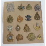 A group of 16 military cap badges.