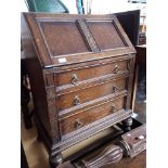 A 1930s carved oak bureau with fitted interior, width 49cm & height 106cm.