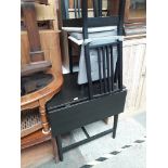 A black drop leaf table and two chairs.