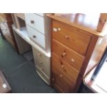 A narrow pine chest of drawers and a veneered dressing table.